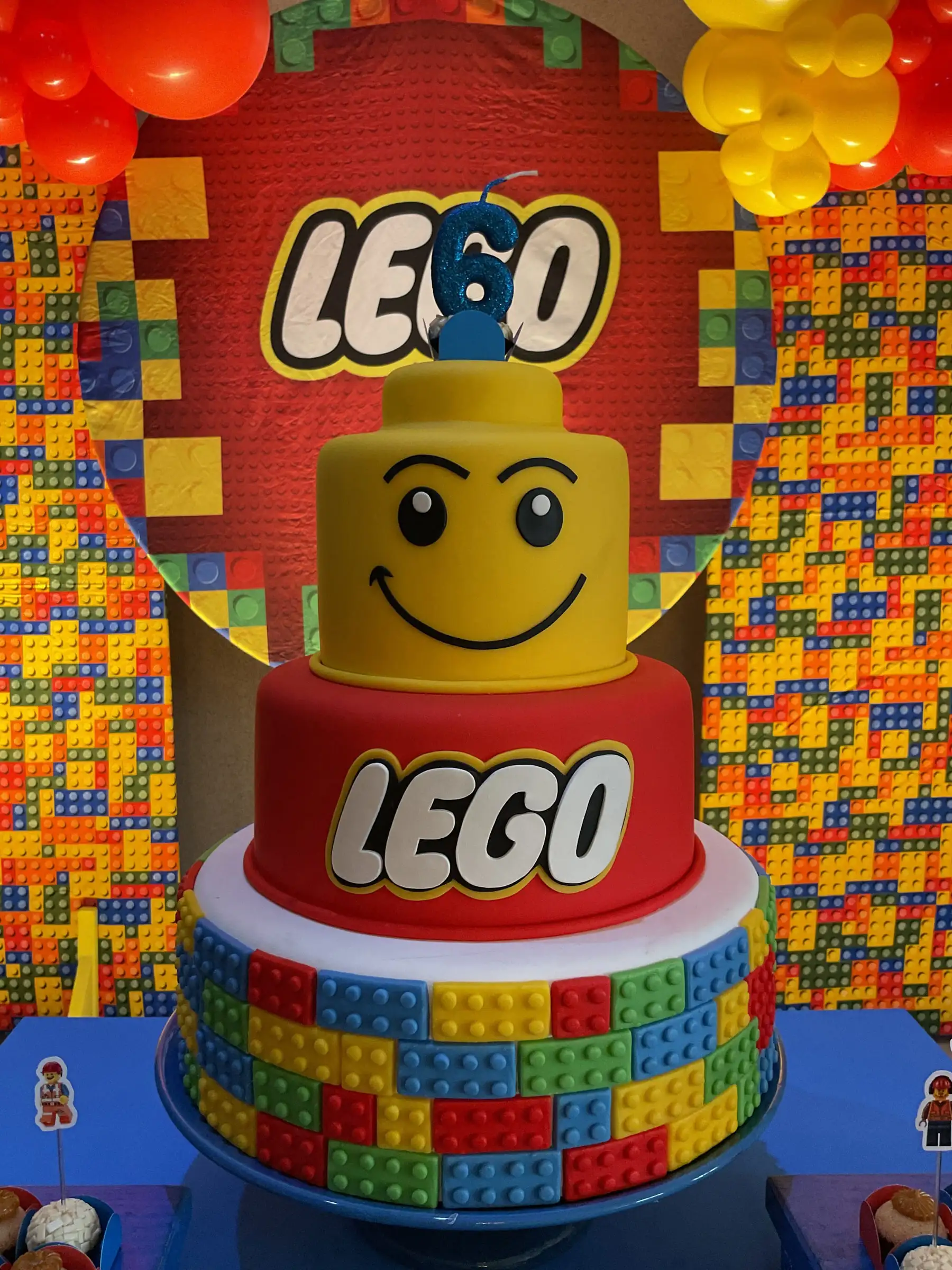 Bolo LEGO com a cabeça sorridente de um bonequinho no topo