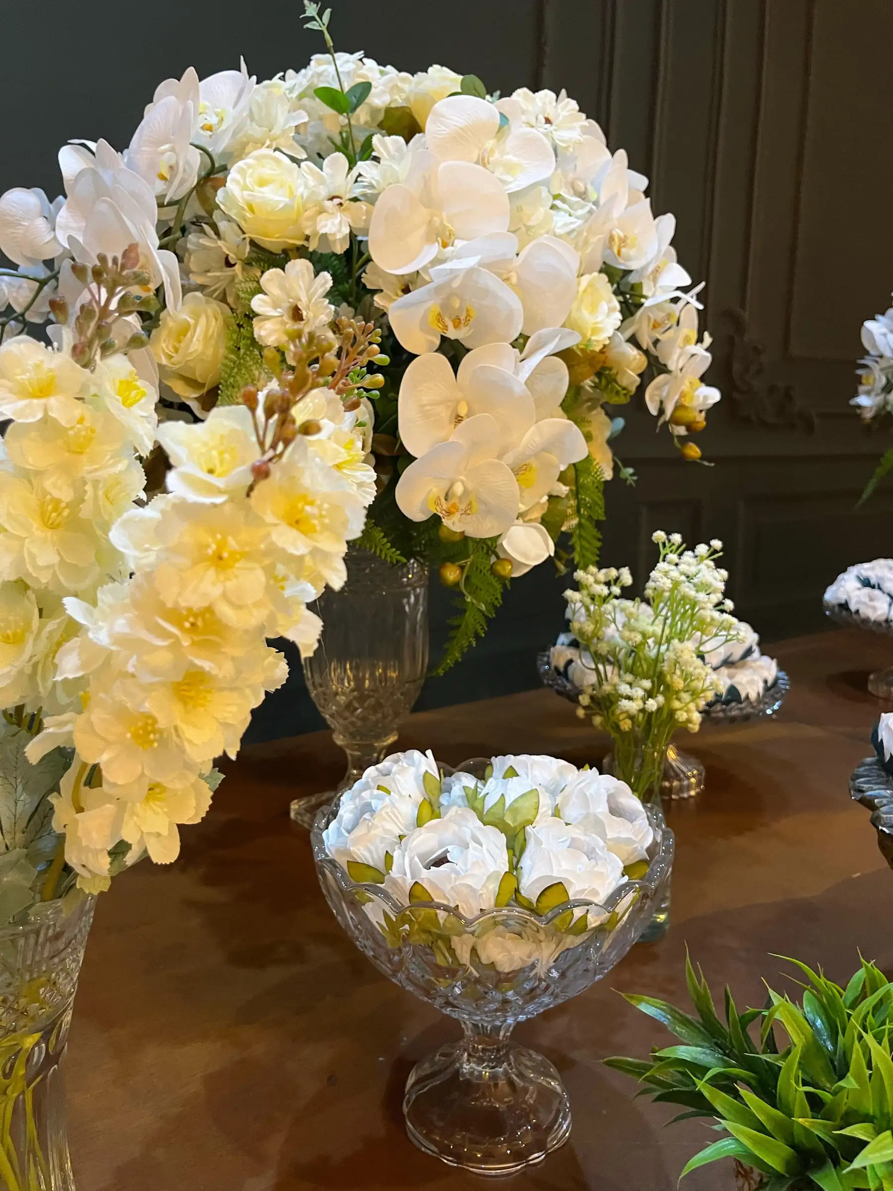 Orquídeas brancas e flores amarelas em arranjo alto
